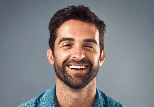Smiling male dental professional wearing blue shirt against gray background