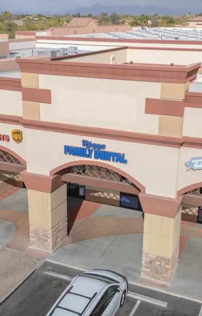 Riggs Family Dental storefront exterior with blue signage in shopping center parking lot.