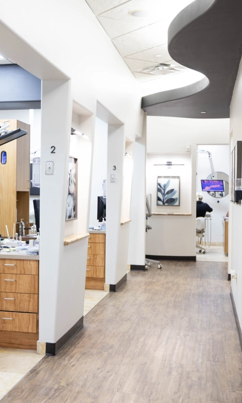 Modern dental office reception area with white walls, wooden flooring, and contemporary furnishings.