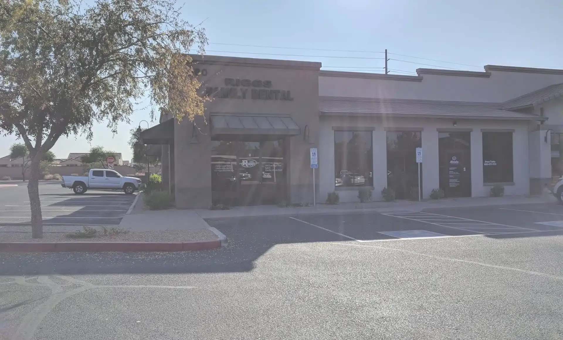 Riggs Family Dental storefront exterior with brick facade and entrance columns on sunny street.