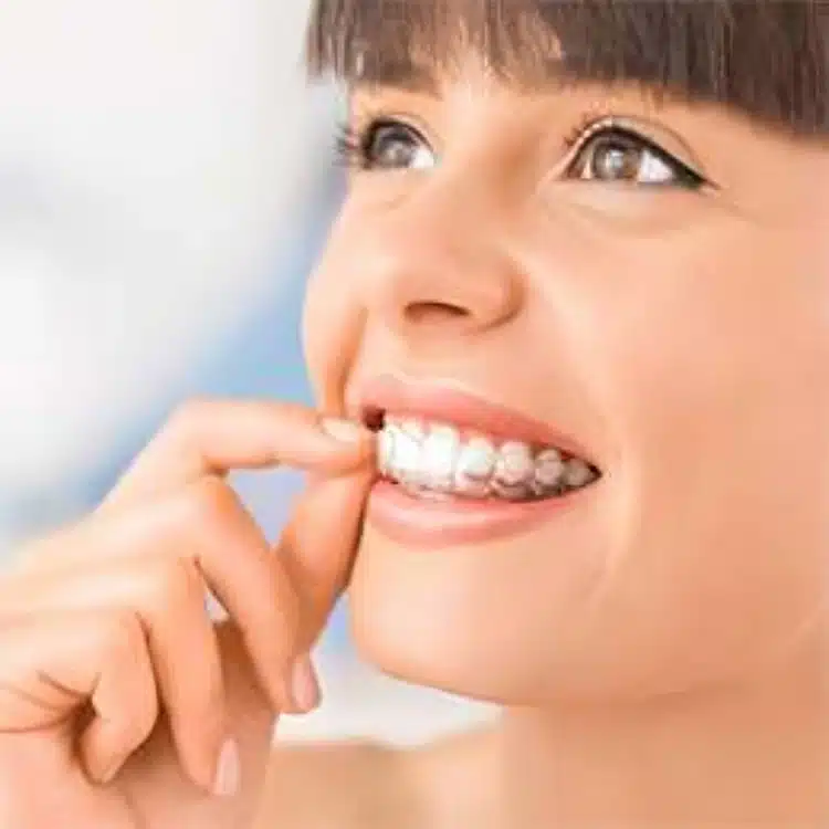 Woman smiling while flossing teeth against blurred background, demonstrating oral hygiene care.