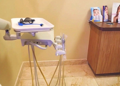 Dental office utility area with sterilization equipment, supplies, and storage cabinet against yellow walls.