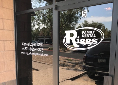 Riggs Family Dental storefront entrance with glass door and window signage displaying business name and contact information.