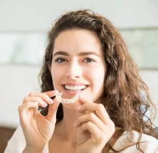 Patient inserting clear Invisalign aligners for teeth straightening